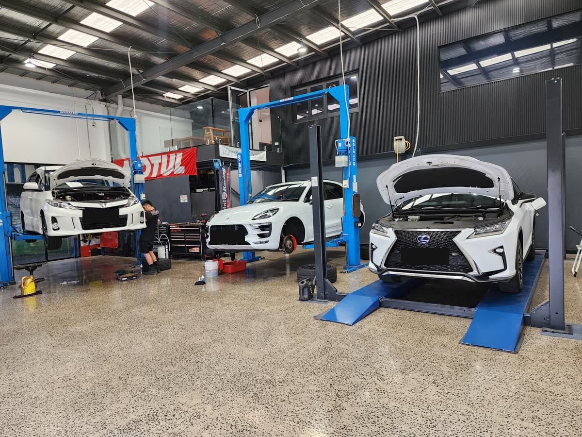 Three cars up on the hoists in the AMS workshop, with a technician working on one of them
